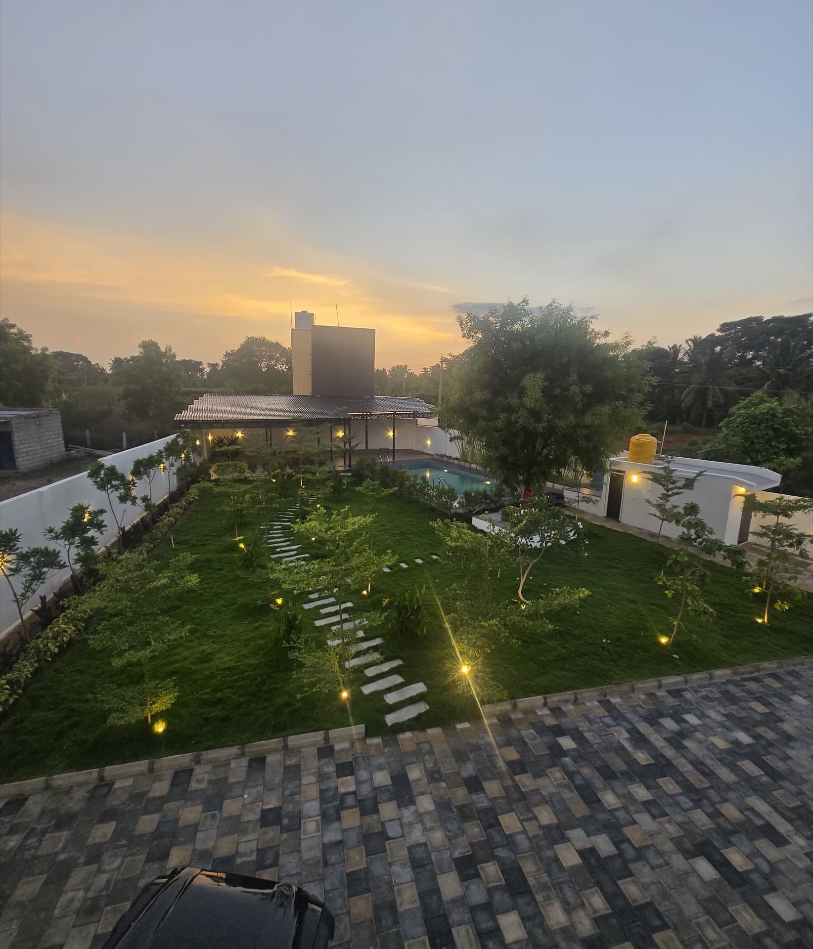 Golden-hour view over the lawn, pool and villa at sunset